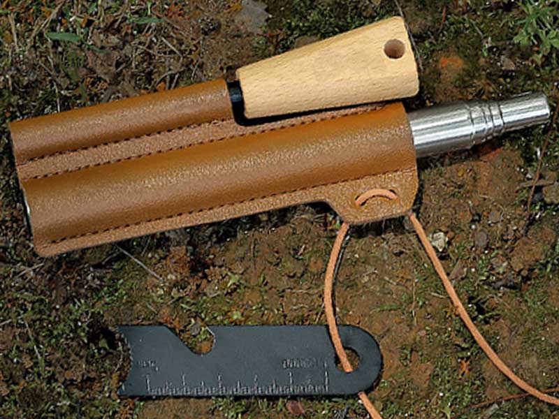 View on The Ground of The Magnesium Fire Starting Rod with Black Striker Steel and Telescopic Blower in a Faux Leather Sheath