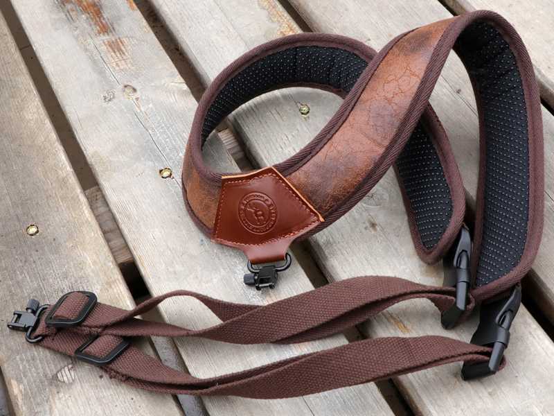 Brown TU Leather and Black Neoprene Padded Hunting Gun Back Harness Sling Fitted with Black Metal QD Swivels and Plastic Side Release Buckles, Shown on Wooden Decking
